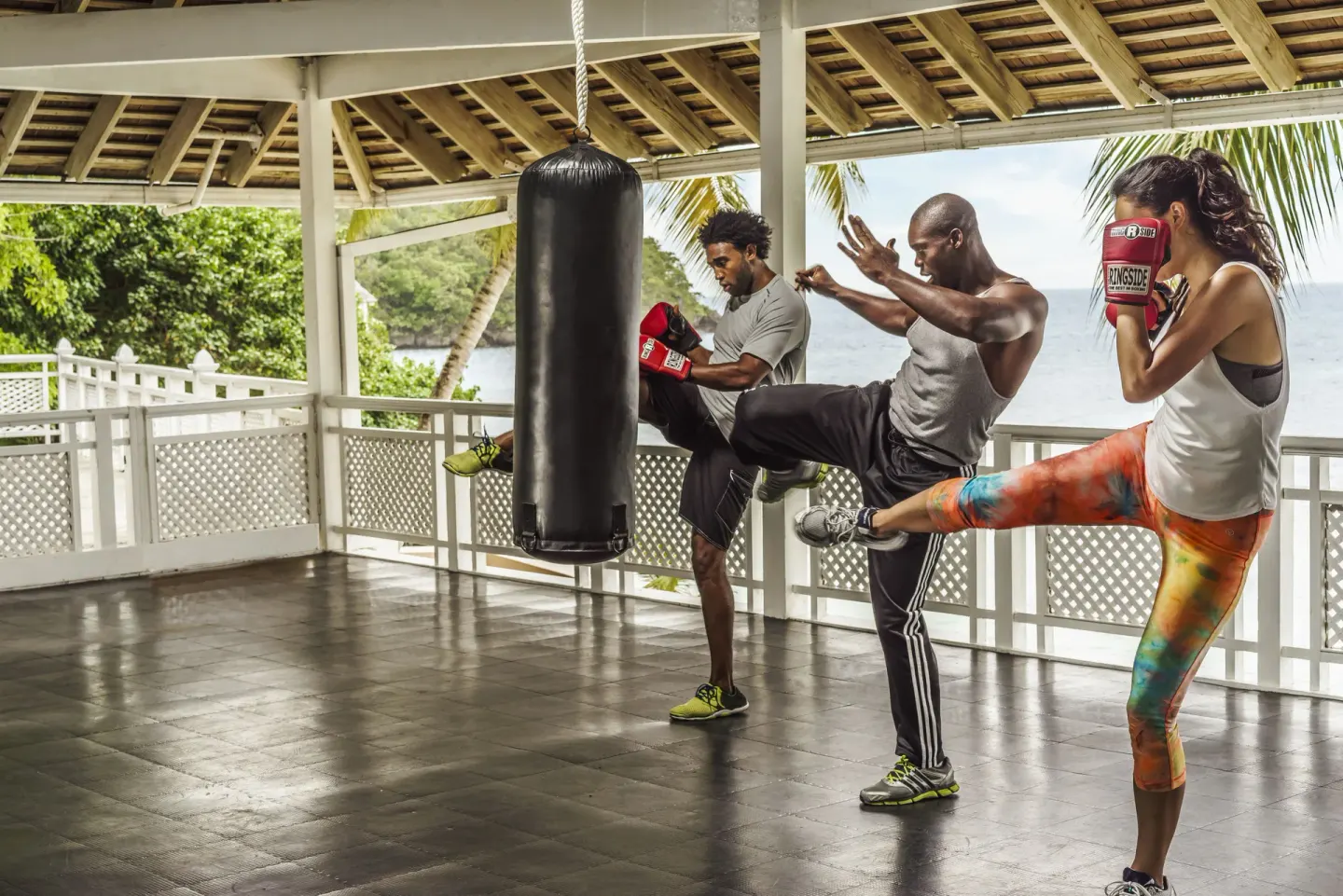 Guests kickbox near a hanging bag in an open-air pavilion at Couples Sans Souci.