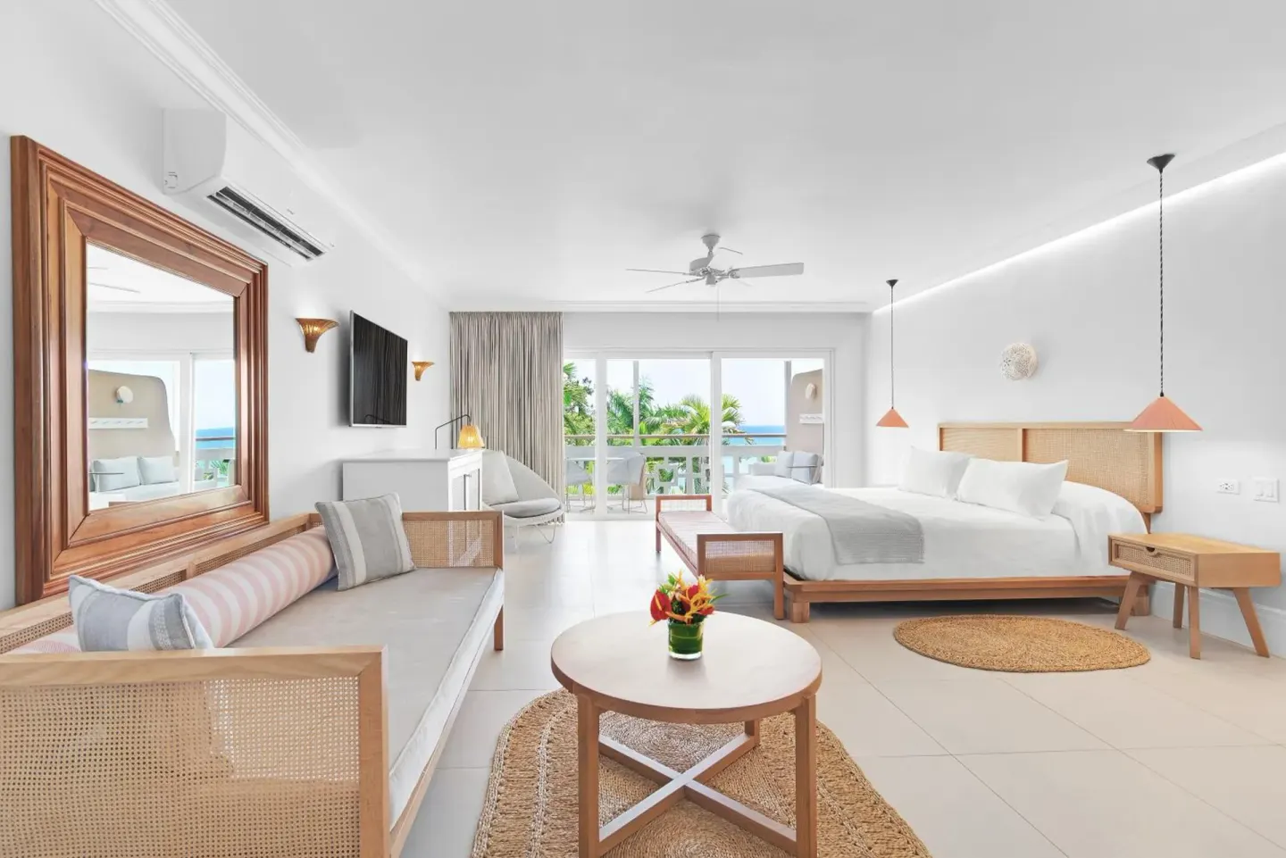 Spacious suite with king bed, sofa seating, and balcony doors at Couples Sans Souci.