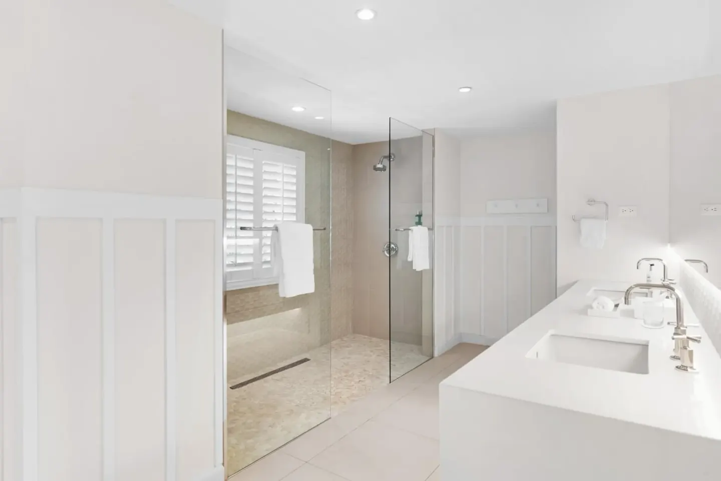 White bathroom with glass shower and double vanity at Couples Sans Souci.