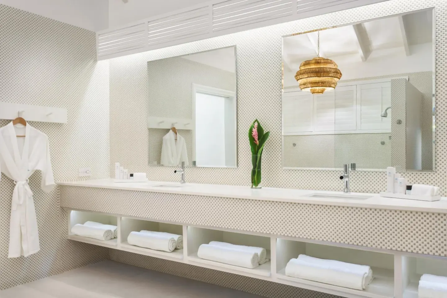Bright bathroom with double sinks, mirrors, towels, and robes at Couples Tower Isle.