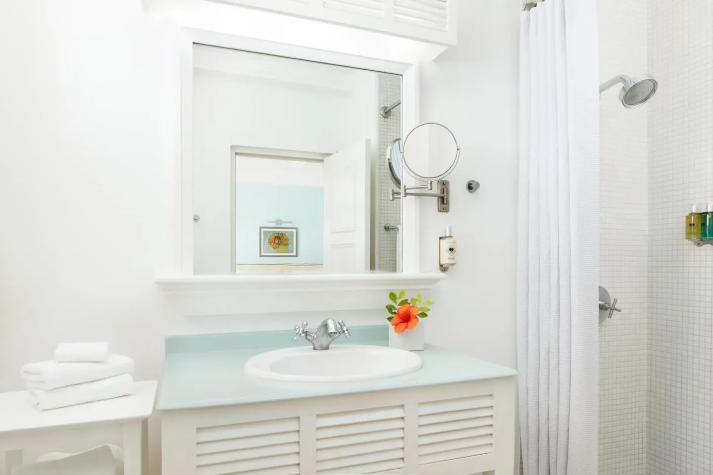 White bathroom vanity and shower with glass amenities at Couples Tower Isle.