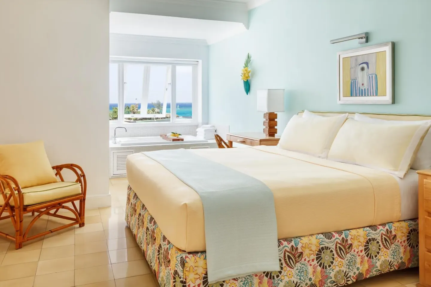 Guest room with king bed, sitting chair, and ocean view at Couples Tower Isle.