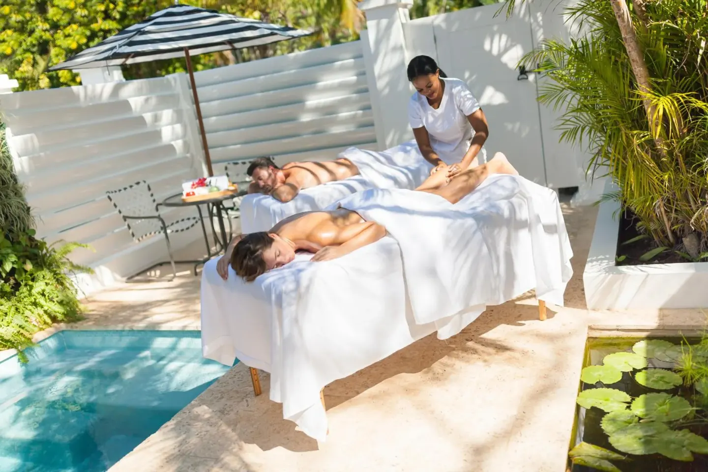 Couple receiving outdoor massages beside a small pool at Couples Tower Isle.