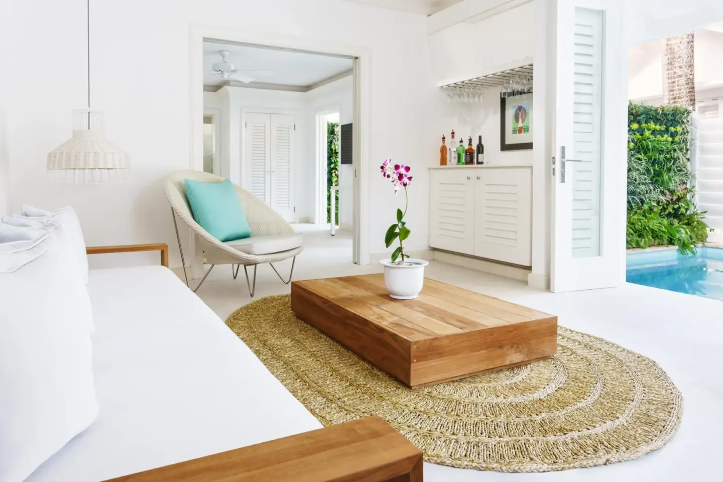 White suite living area with low table and poolside doors at Couples Tower Isle.