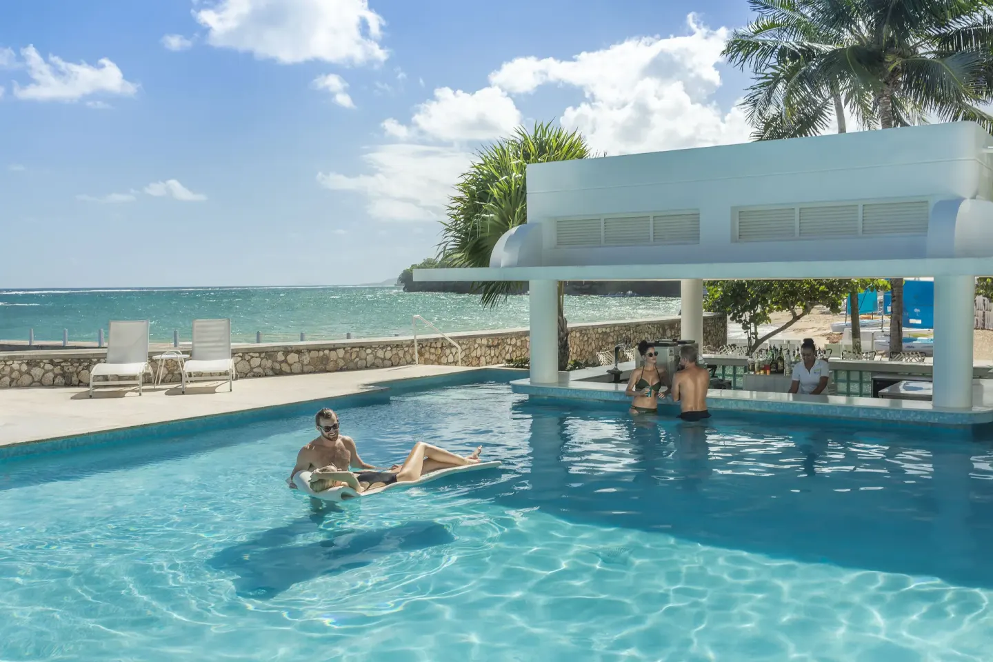 Swim-up pool bar with ocean views and guests in the water at Couples Tower Isle.