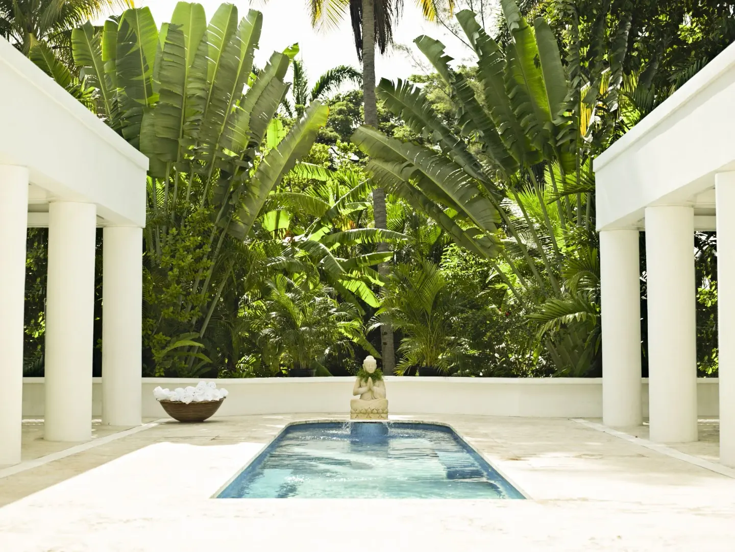 Courtyard reflecting pool with white columns and lush tropical plants at Couples Tower Isle.
