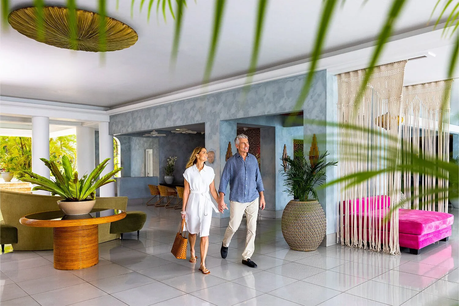 Couple walking through the bright lobby with tropical plants at Couples Tower Isle.