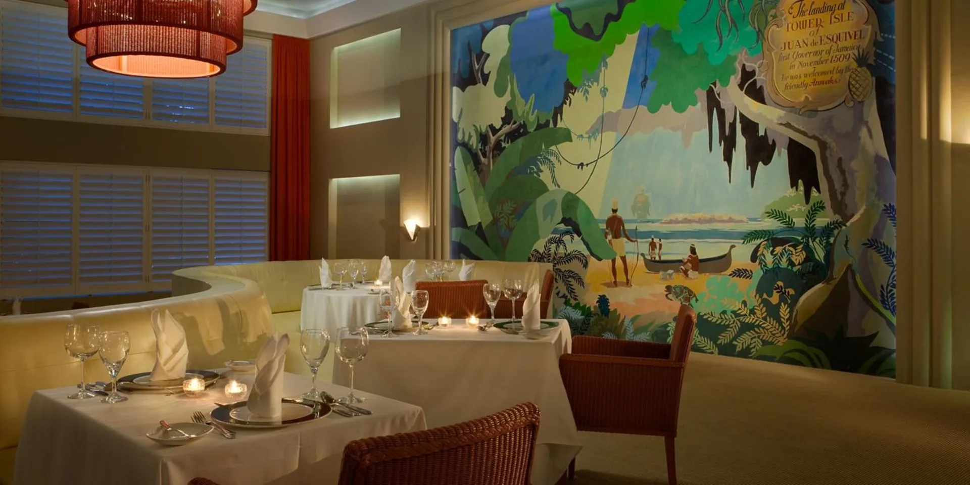 Fine dining room with mural, white linens, and candlelit tables at Couples Tower Isle.