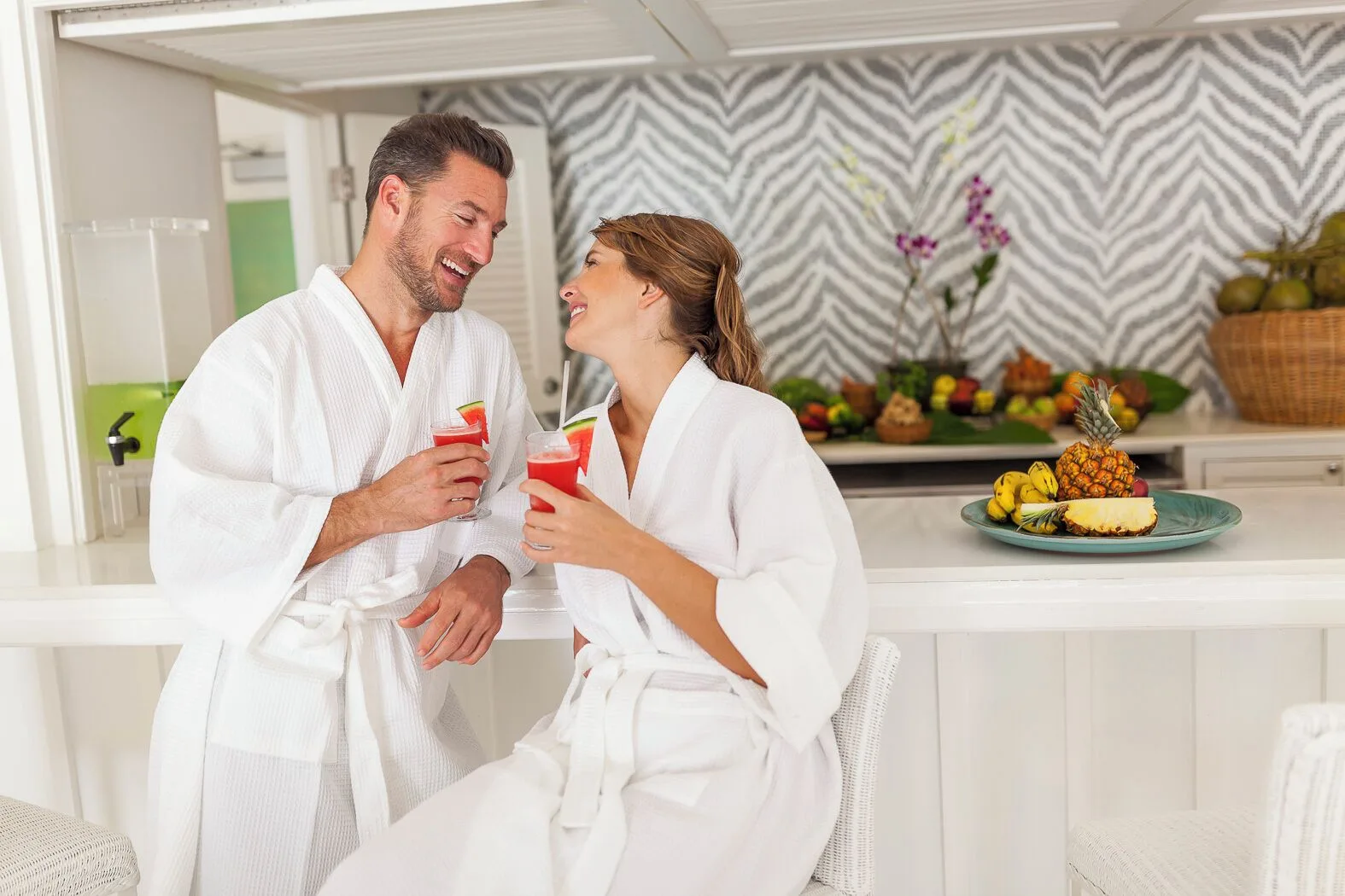 Guests in robes hold fruit drinks at a juice bar counter at Couples Tower Isle.