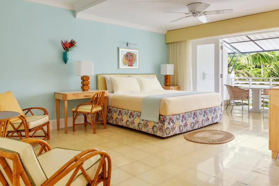 Garden Junior Suite with king bed, wicker seating, desk and balcony at Couples Tower Isle.