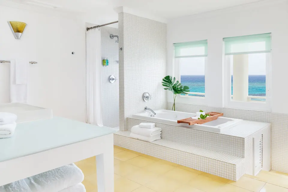 Ocean Junior Suite bathroom with soaking tub and sea-view windows at Couples Tower Isle.
