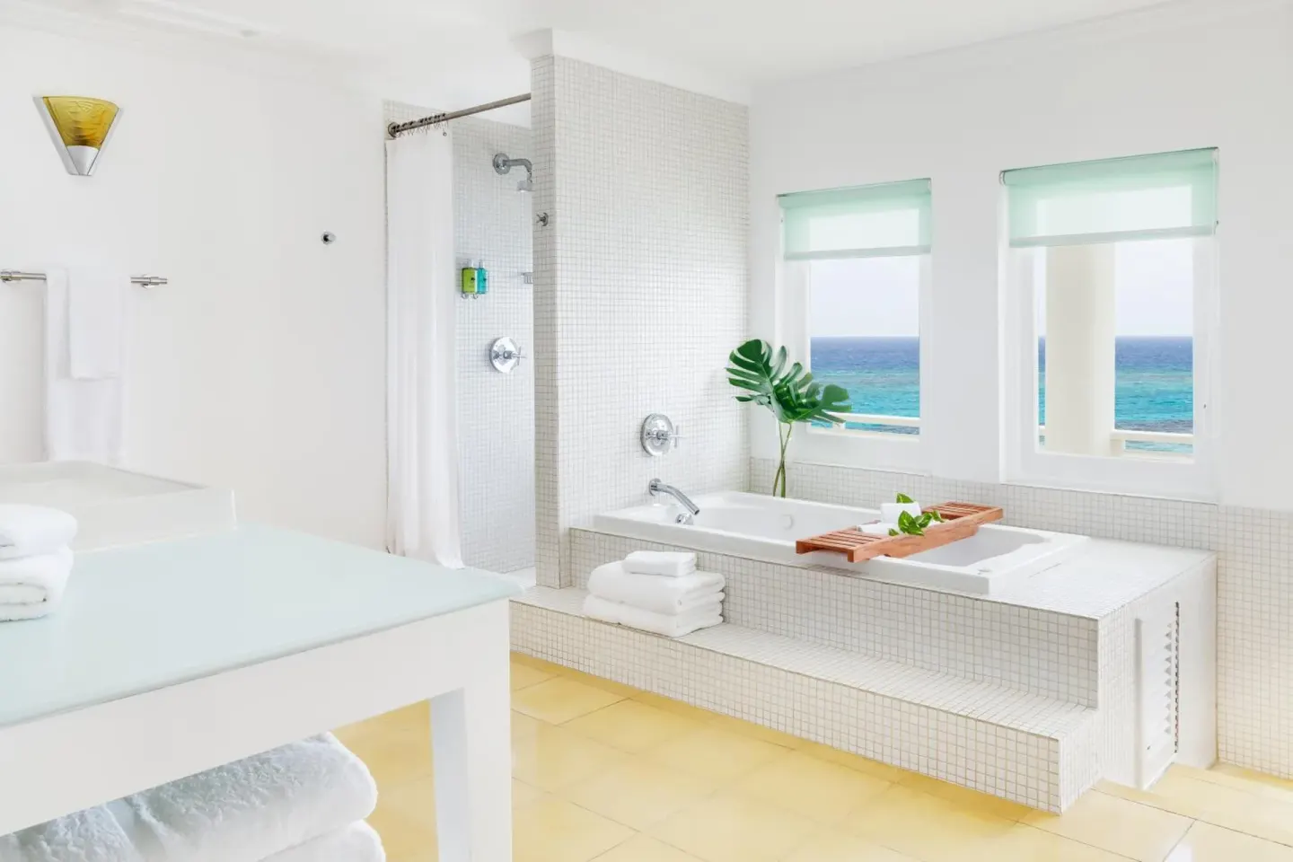 Ocean Junior Suite bathroom with white tile, soaking tub, and sea views at Couples Tower Isle.