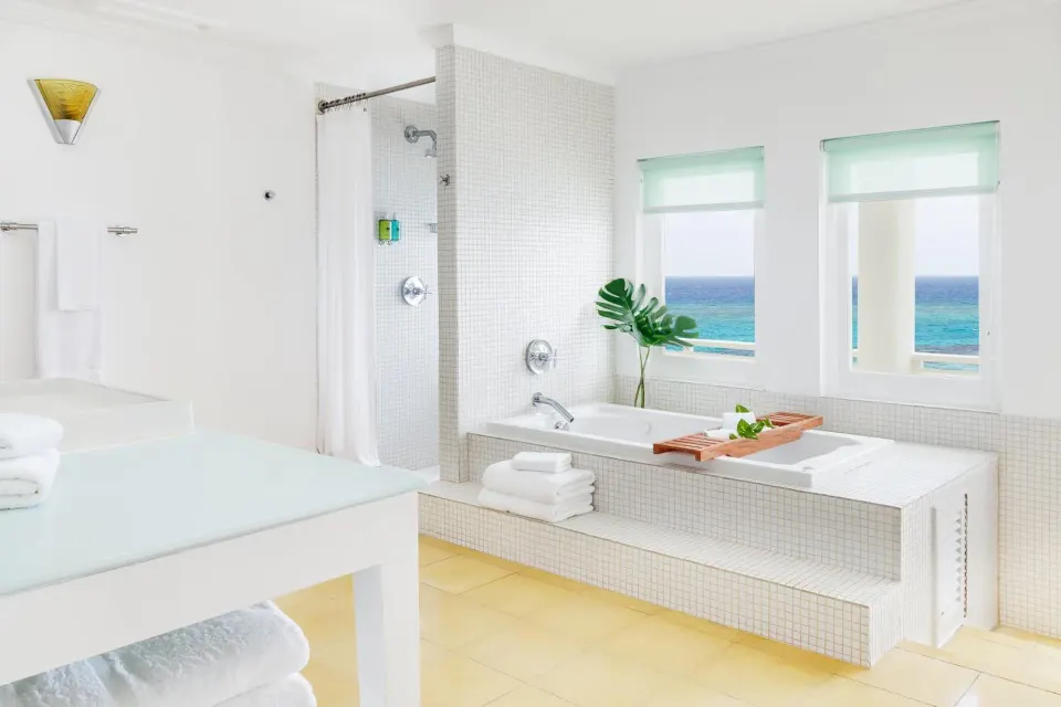 Ocean Junior Suite bathroom with white tile, soaking tub, and sea views at Couples Tower Isle.