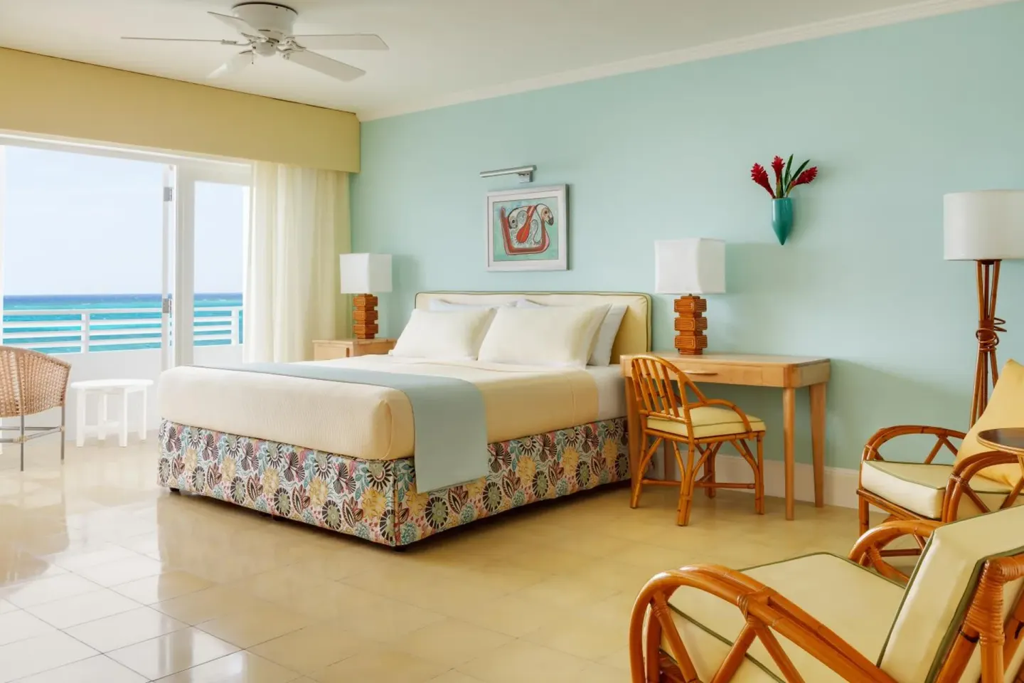 Ocean Junior Suite king bed beside a desk and rattan chairs with sea view at Couples Tower Isle.