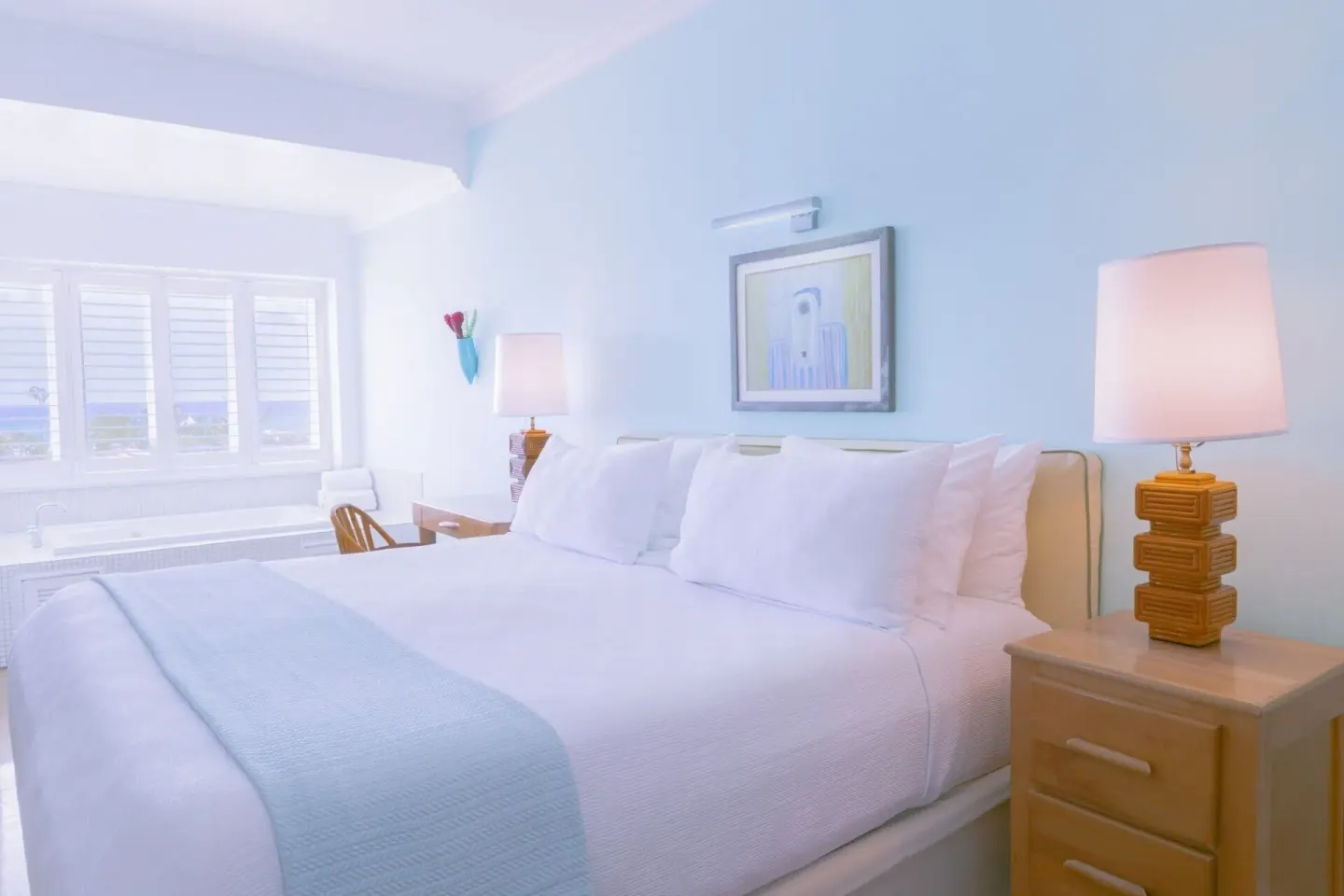 One Bedroom Ocean Suite bed with lamps and shuttered window at Couples Tower Isle.
