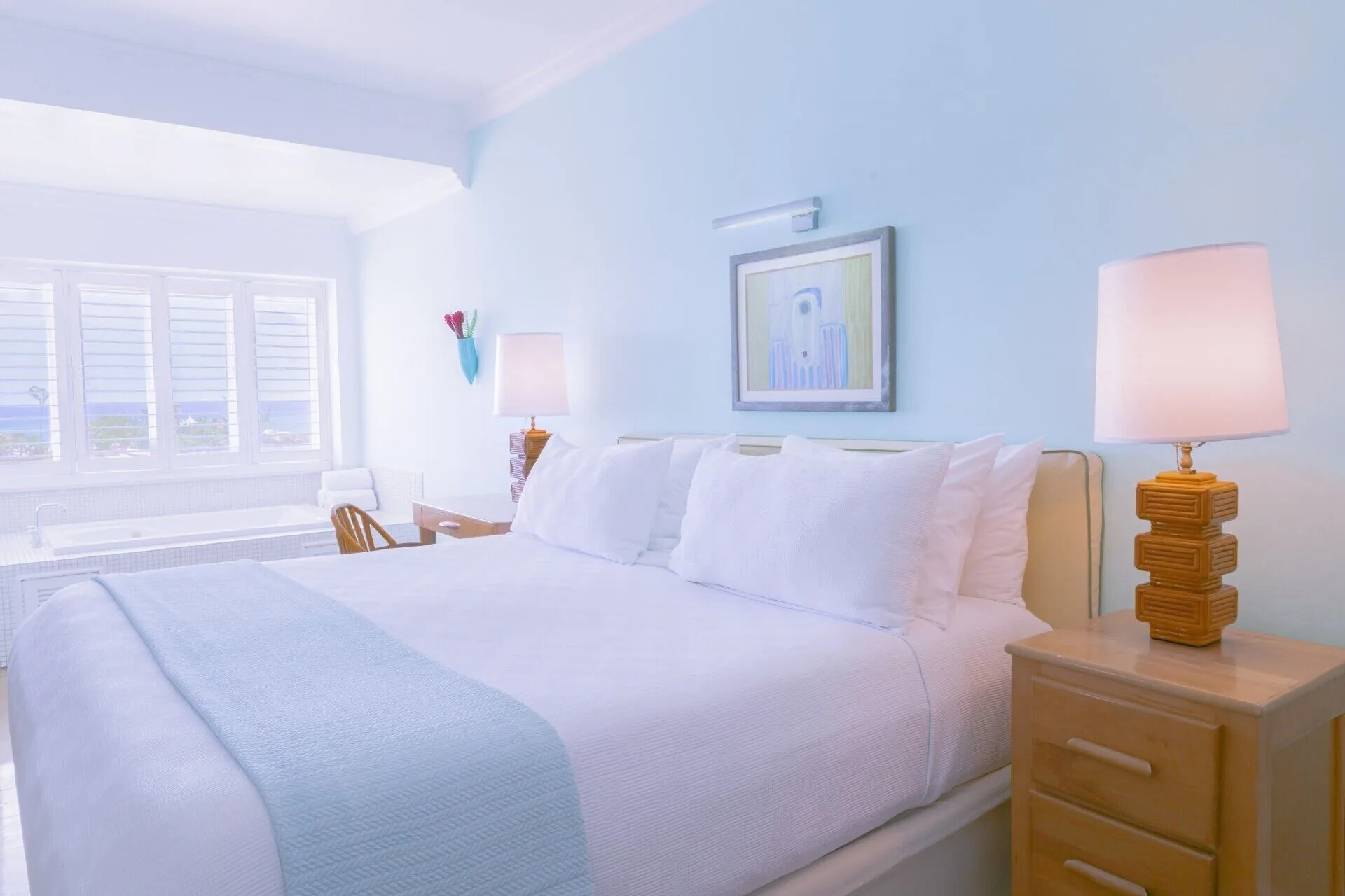 One Bedroom Ocean Suite bed with lamps and shuttered window at Couples Tower Isle.