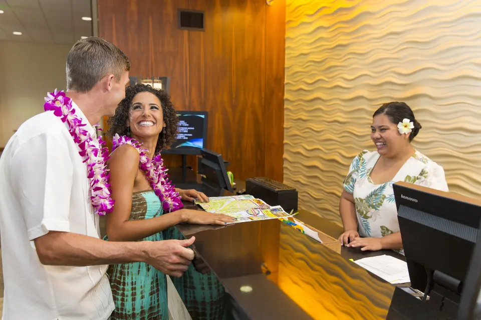 Guests with leis check in at the front desk at Courtyard King Kamehameha's Kona Beach Hotel.