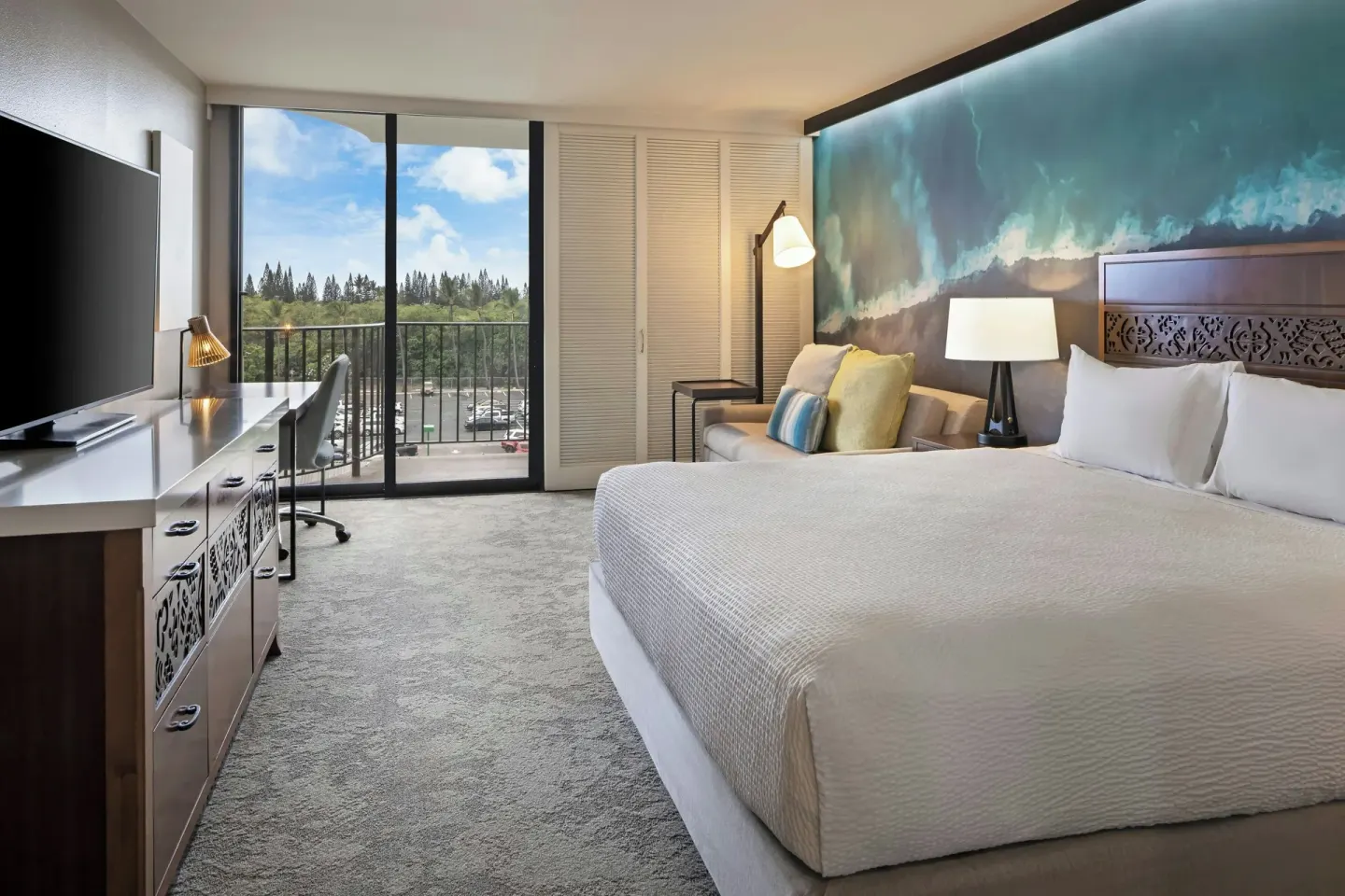 King guest room at Courtyard King Kamehameha's Kona Beach Hotel with desk, balcony, and hillside view.