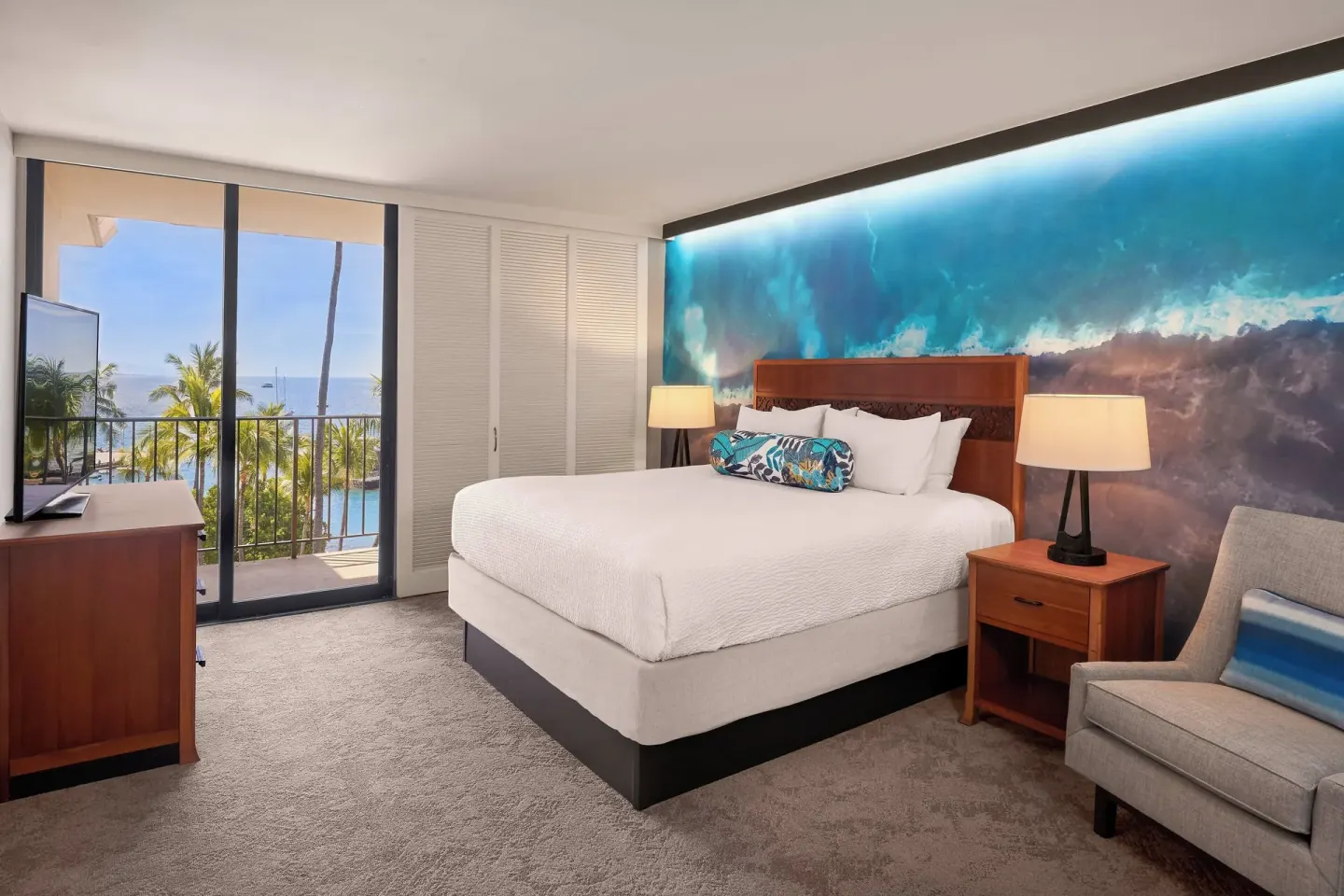 Ocean-view king guest room at Courtyard King Kamehameha's Kona Beach Hotel with balcony and wave mural.