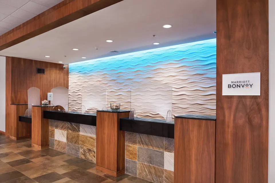 Empty reception counters with wave-textured wall at Courtyard King Kamehameha's Kona Beach Hotel.