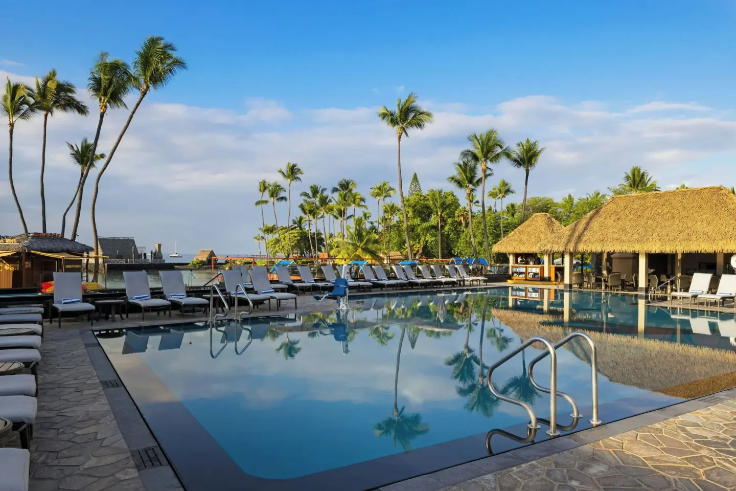 Resort pool with thatched roof and palms at Courtyard King Kamehameha's Kona Beach Hotel.