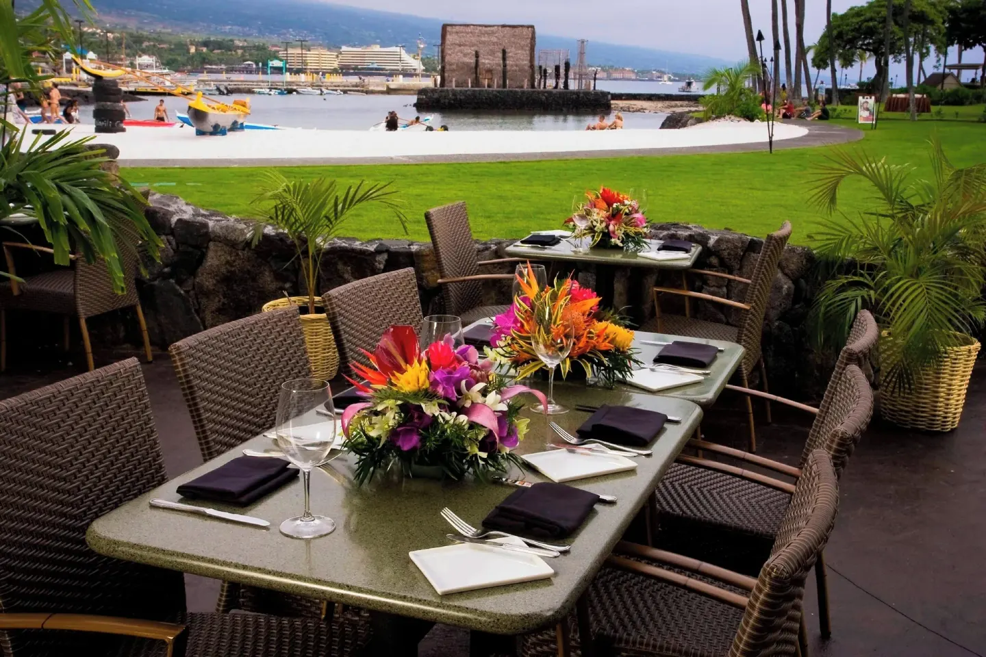 Outdoor dining tables overlook the beach at Courtyard King Kamehameha's Kona Beach Hotel.