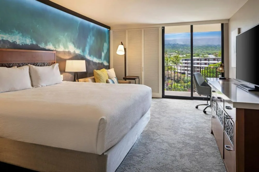 King guest room with sofa bed, balcony, and mountain view at Courtyard King Kamehameha's Kona Beach Hotel.