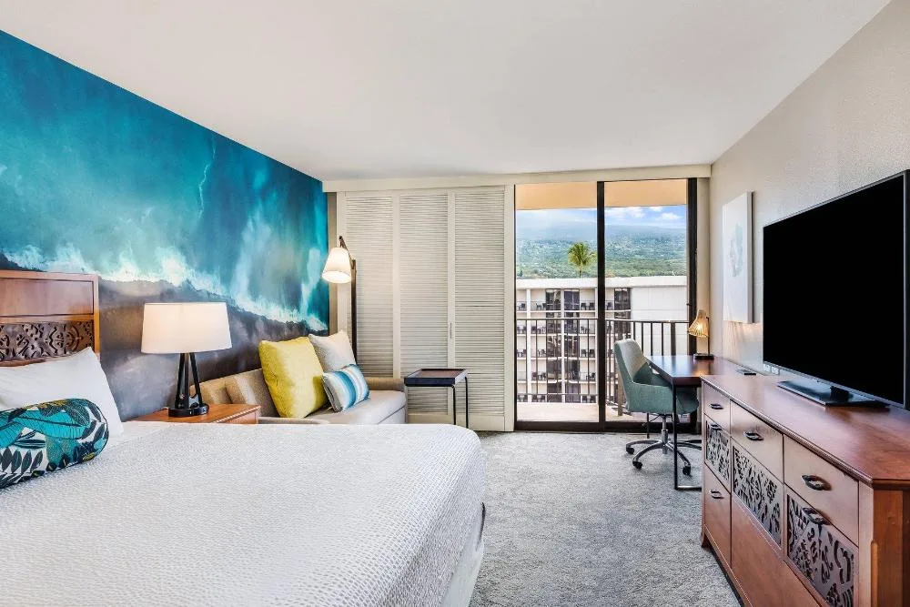 Resort view king guest room with sofa bed and balcony at Courtyard King Kamehameha's Kona Beach Hotel.