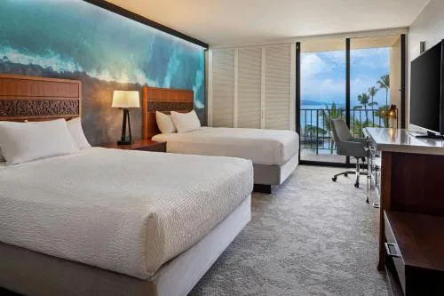 Two-bed guest room opening to an oceanfront balcony at Courtyard King Kamehameha's Kona Beach Hotel.