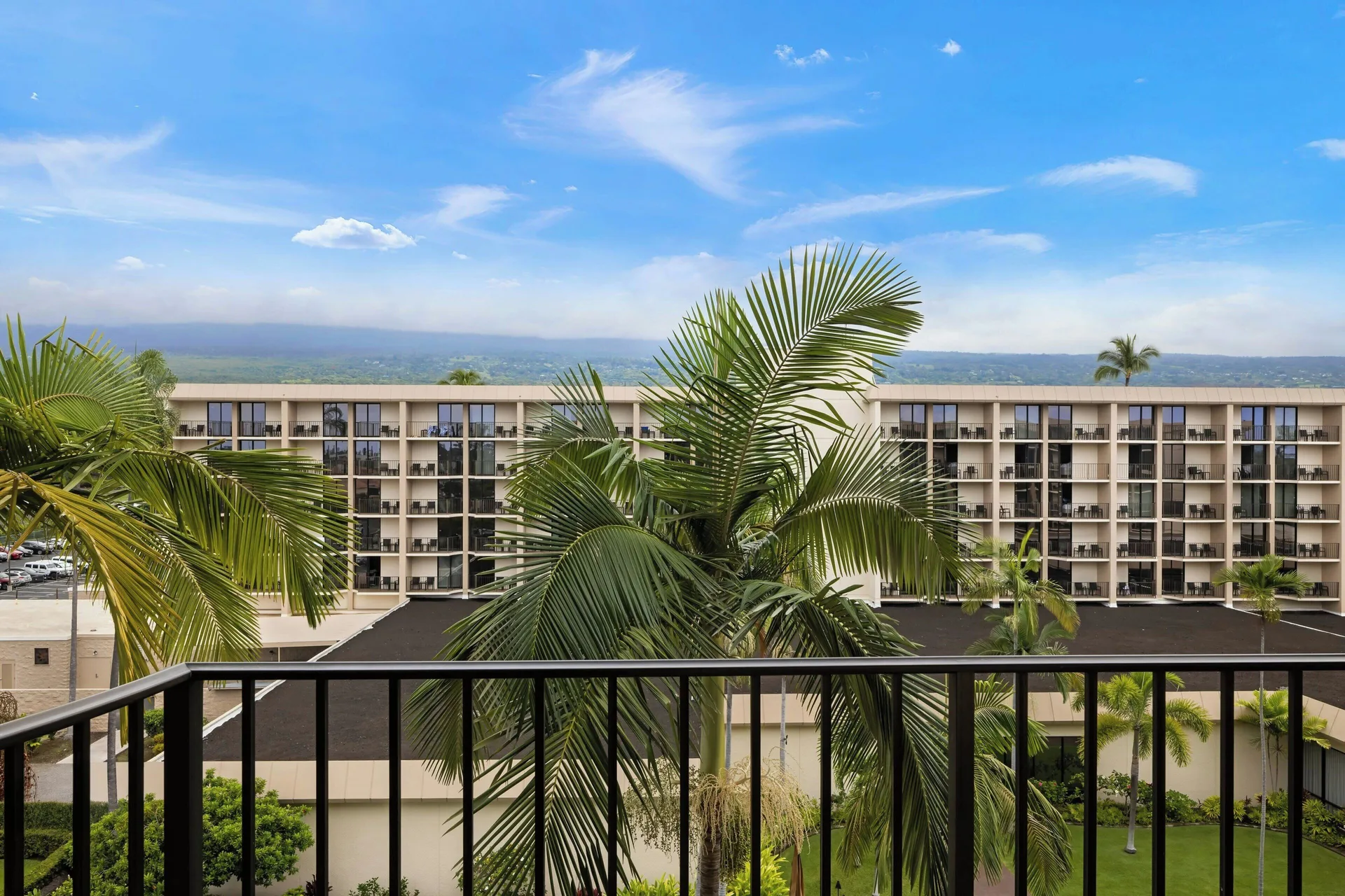 Balcony view of palms, hotel balconies, and mountains at Courtyard King Kamehameha's Kona Beach Hotel.
