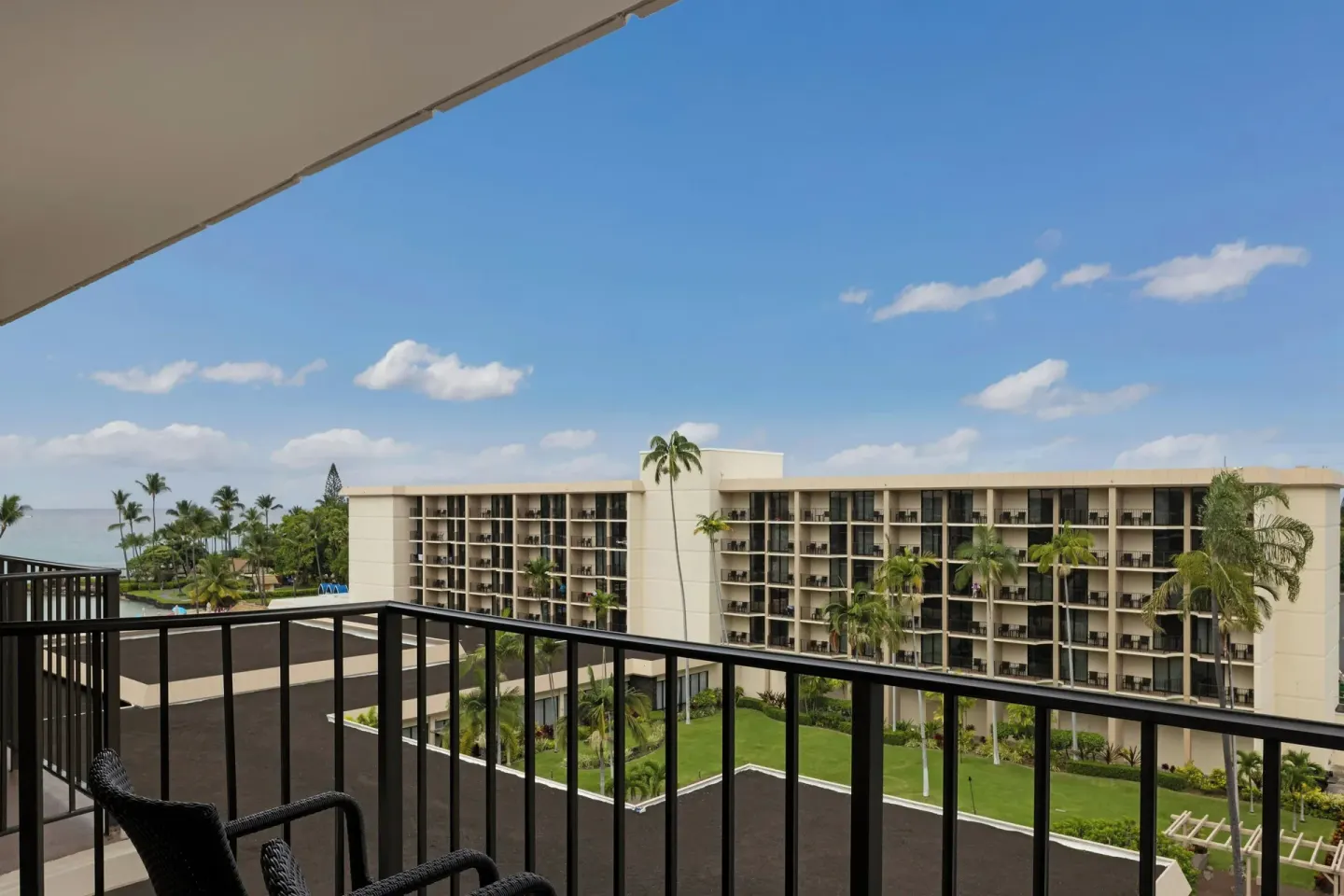 Balcony with chairs and resort buildings at Courtyard King Kamehameha's Kona Beach Hotel.