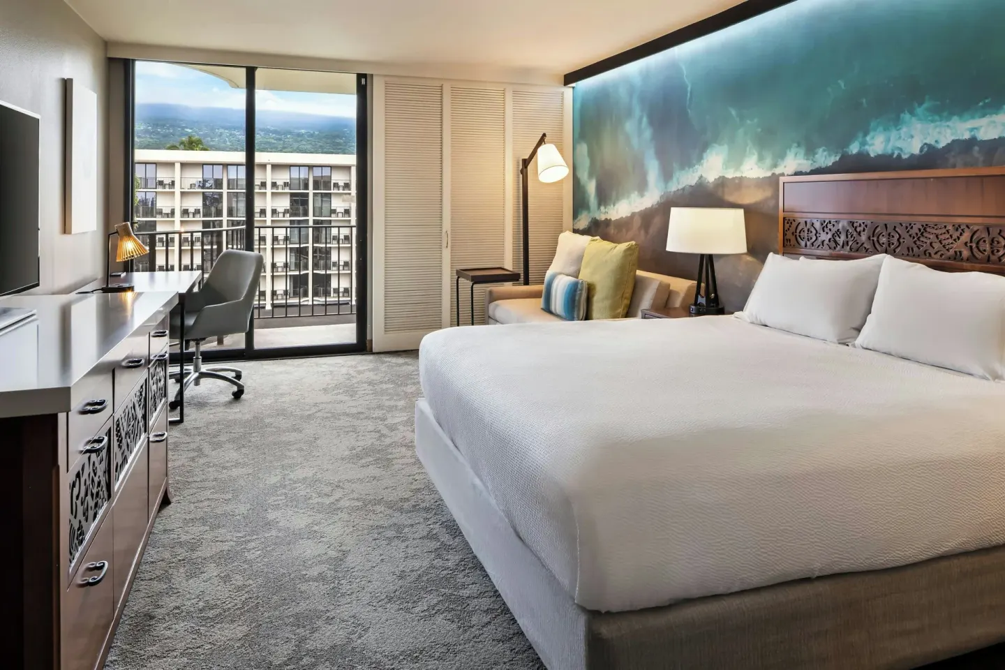Room with king bed, sofa bed, balcony, and mountain view at Courtyard King Kamehameha's Kona Beach Hotel.