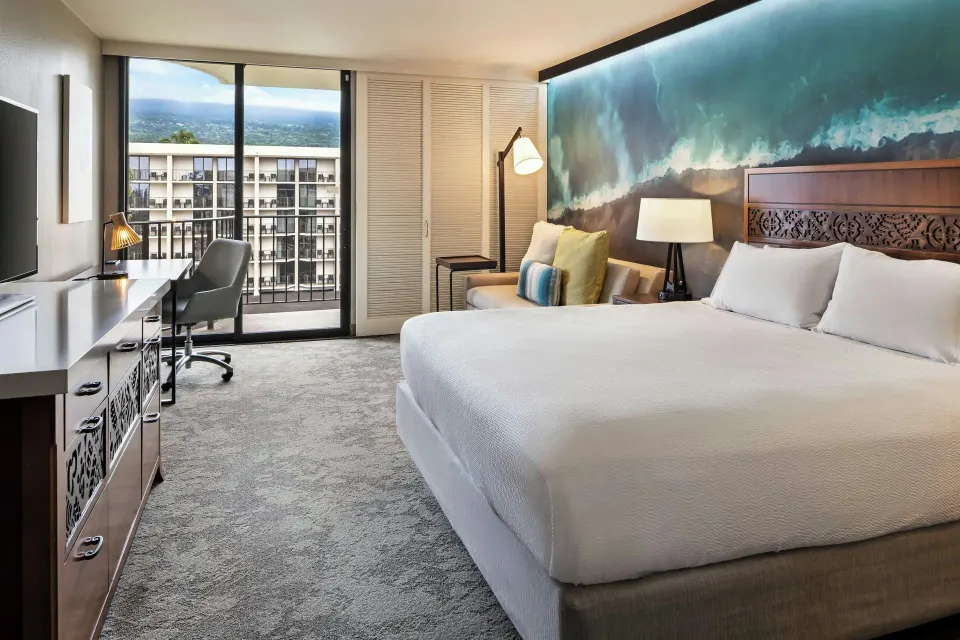 Room with king bed, sofa bed, balcony, and mountain view at Courtyard King Kamehameha's Kona Beach Hotel.