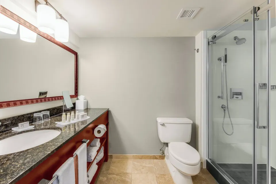 Suite bathroom with vanity and glass shower at Courtyard King Kamehameha's Kona Beach Hotel.
