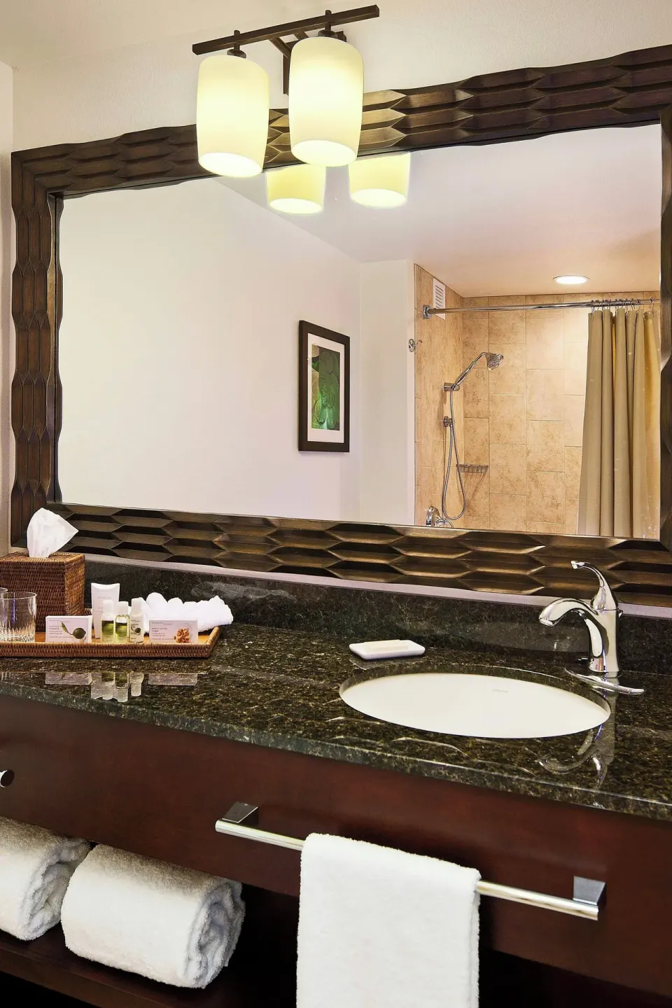 Bathroom vanity and mirror in a suite at Courtyard King Kamehameha's Kona Beach Hotel.