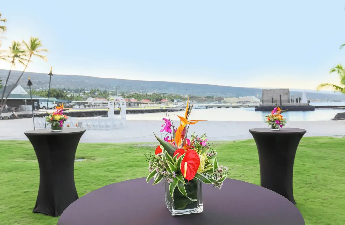 Cocktail tables with tropical flowers on the lawn at Courtyard King Kamehameha's Kona Beach Hotel.