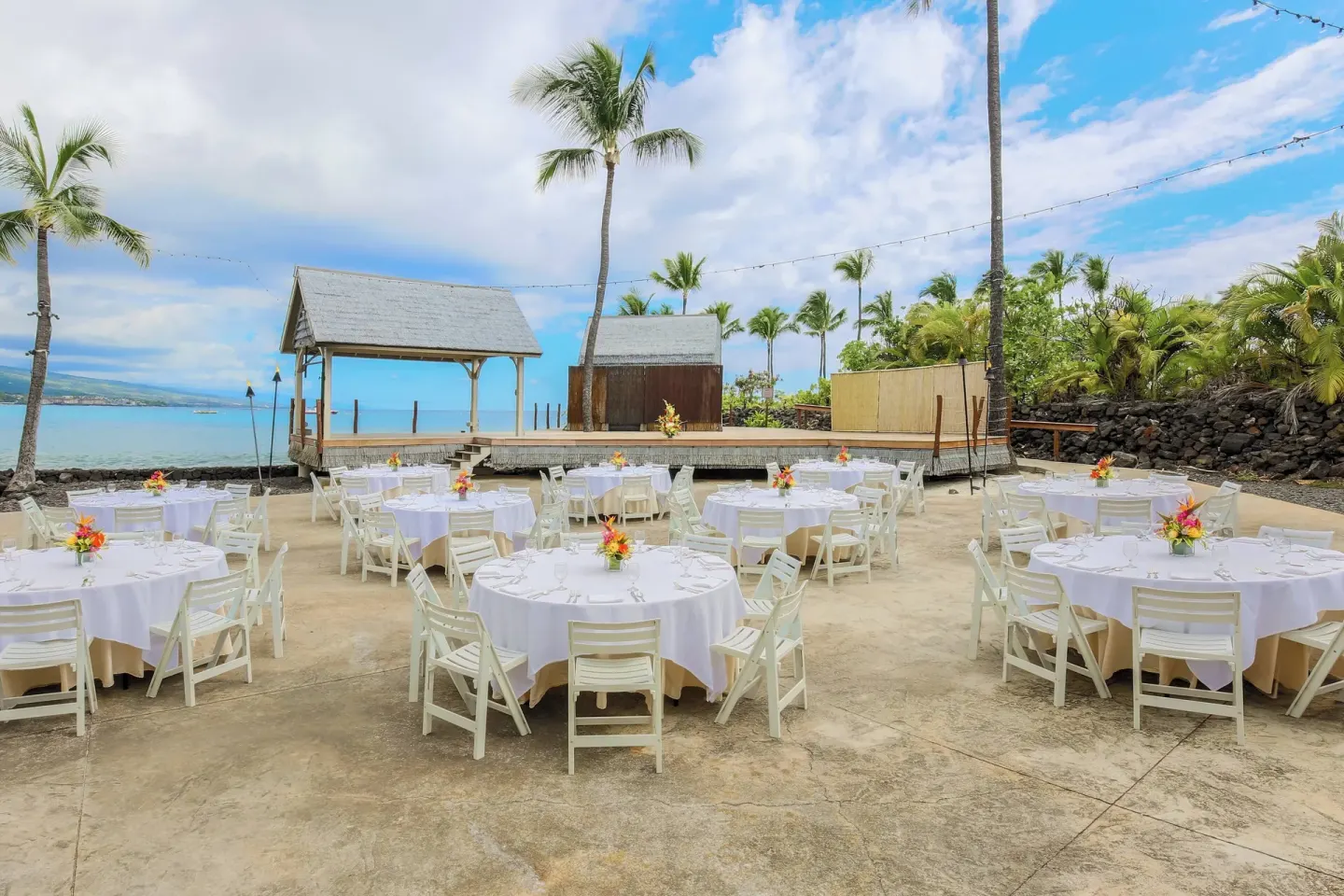 Outdoor banquet tables and stage by the ocean at Courtyard King Kamehameha's Kona Beach Hotel.