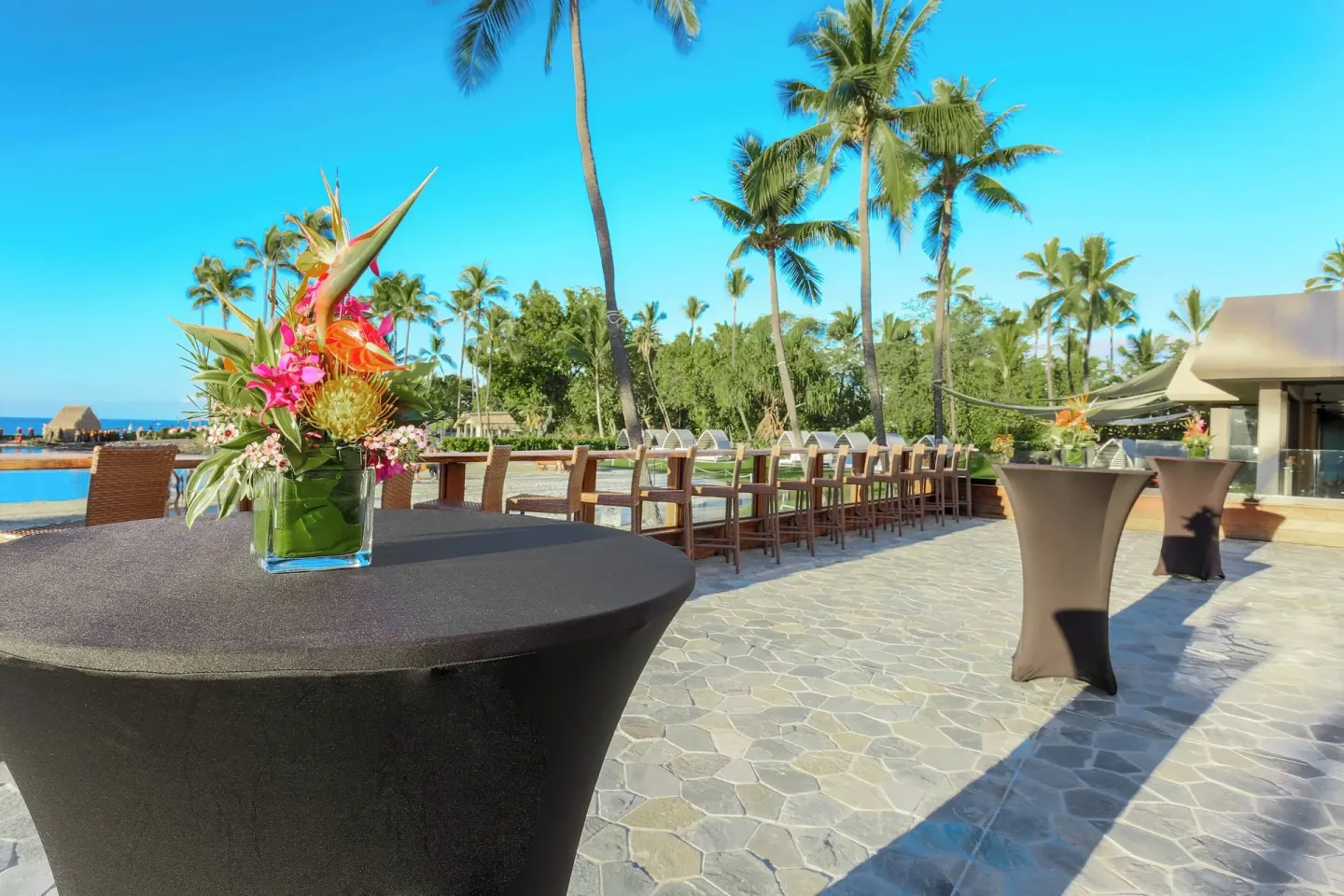 Outdoor event terrace at Courtyard King Kamehameha's Kona Beach Hotel with cocktail tables and flowers.