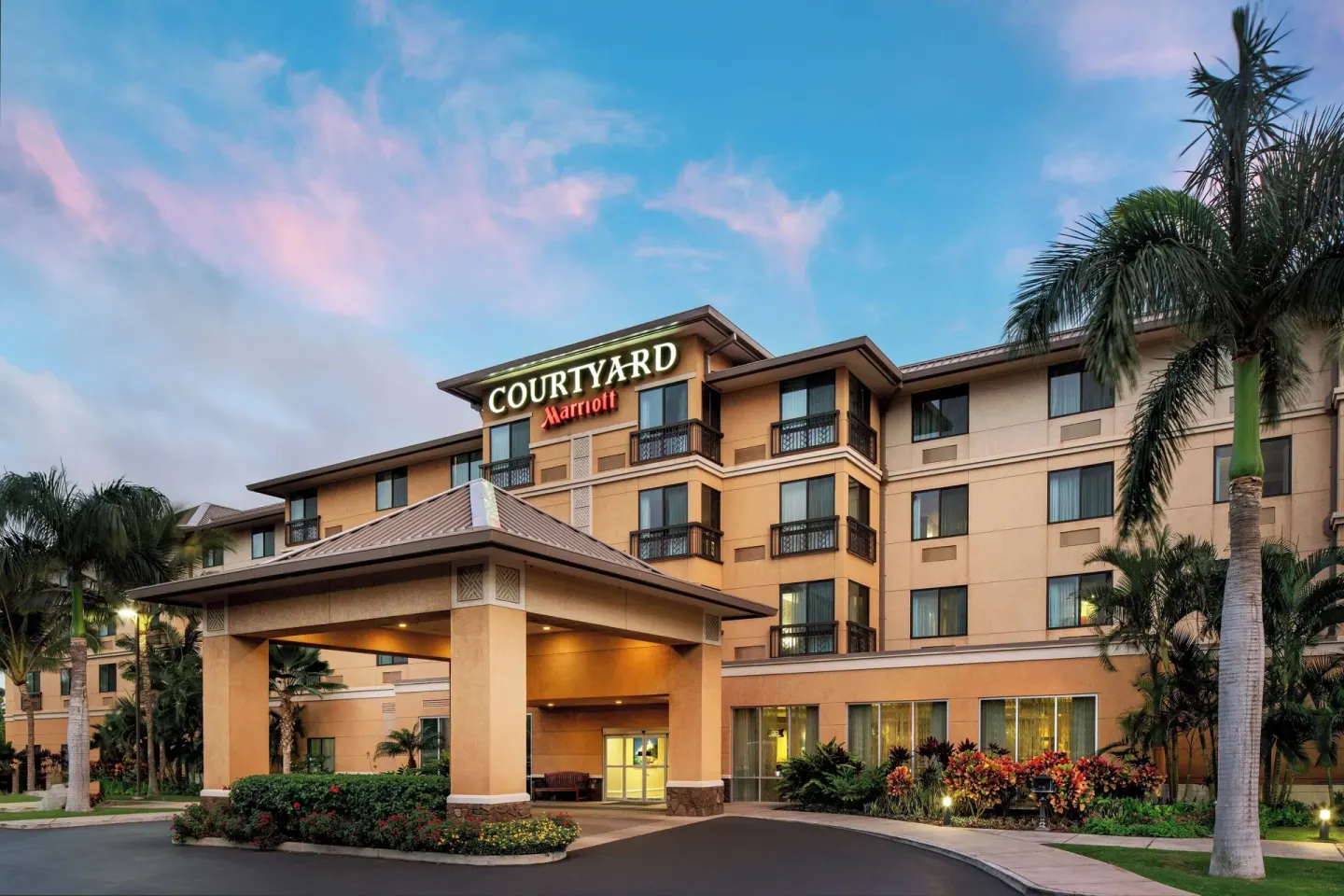 Hotel exterior and covered entrance at Courtyard Maui Kahului Airport at dusk.