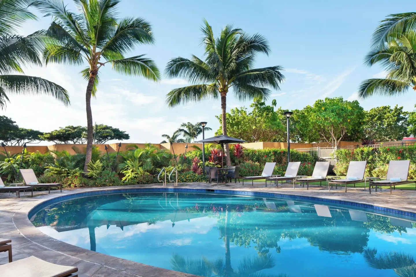 Palm-lined outdoor pool with lounge chairs at Courtyard Maui Kahului Airport.