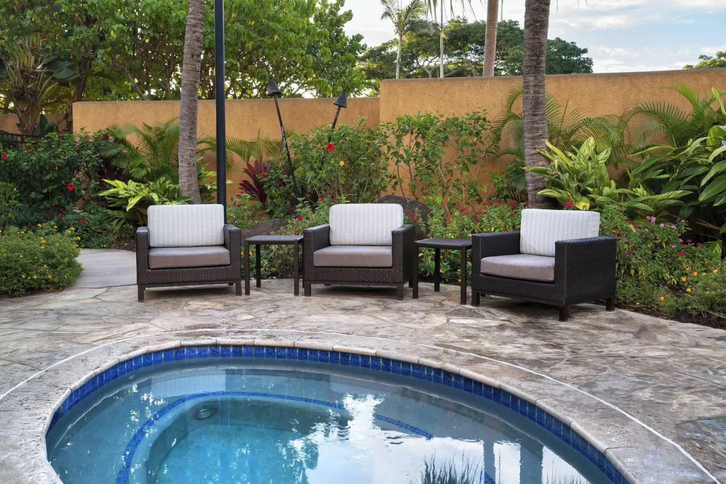 Whirlpool patio with cushioned chairs and tropical plants at Courtyard Maui Kahului Airport.