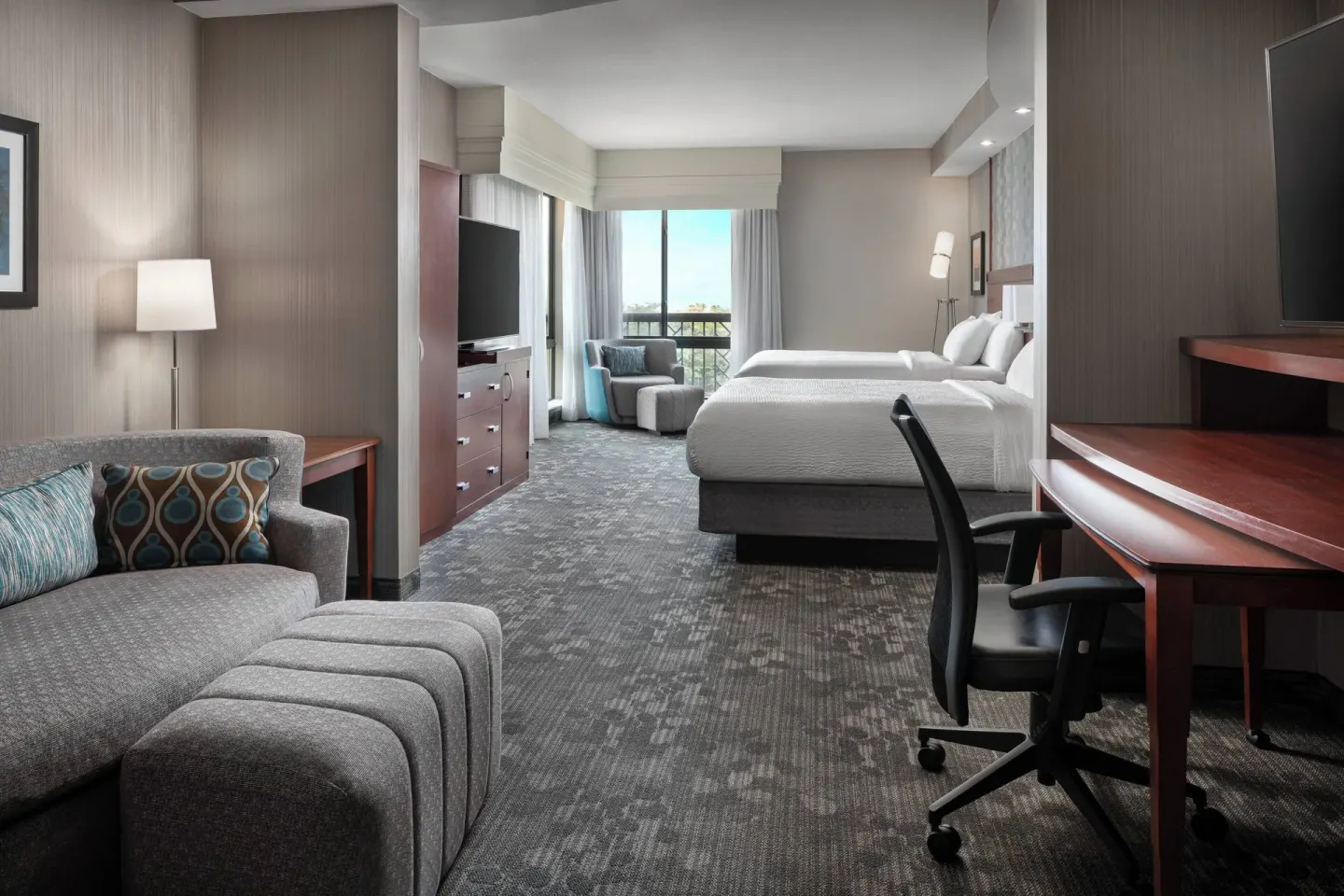 Junior room with two beds, sofa, desk, and balcony at Courtyard Maui Kahului Airport.