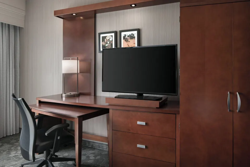 Guest room desk, TV, chair, and wardrobe at Courtyard Maui Kahului Airport.