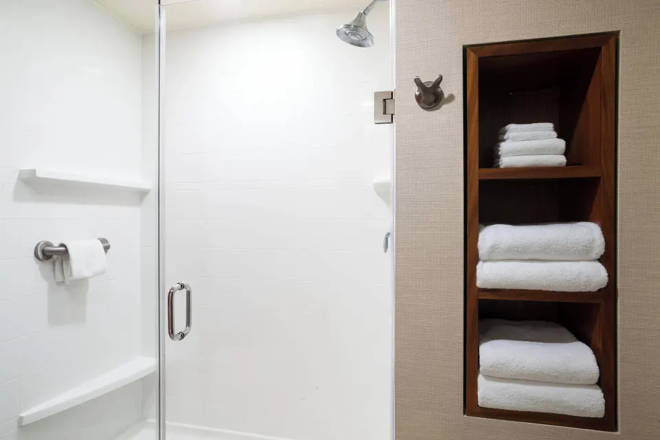 One-bedroom suite shower and towel shelves at Courtyard Maui Kahului Airport.