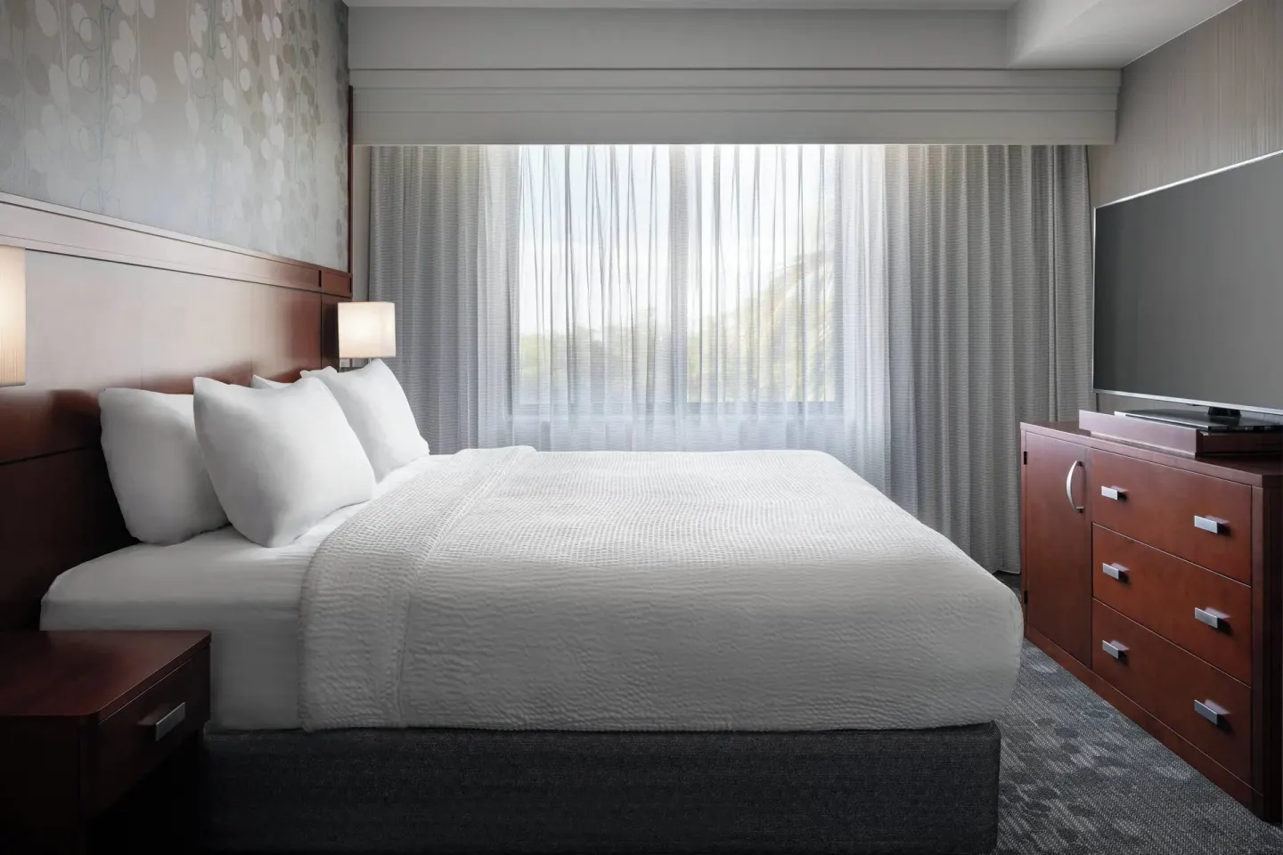 One-bedroom suite bedroom with king bed and TV at Courtyard Maui Kahului Airport.