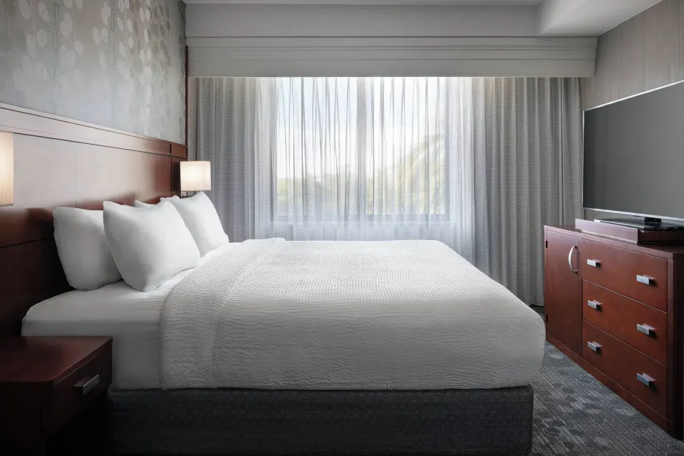 One-bedroom suite bedroom with king bed and TV at Courtyard Maui Kahului Airport.