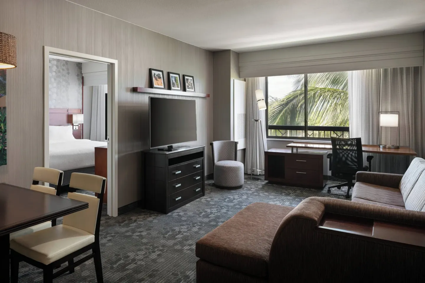 One-bedroom suite living room with desk and sofa at Courtyard Maui Kahului Airport.
