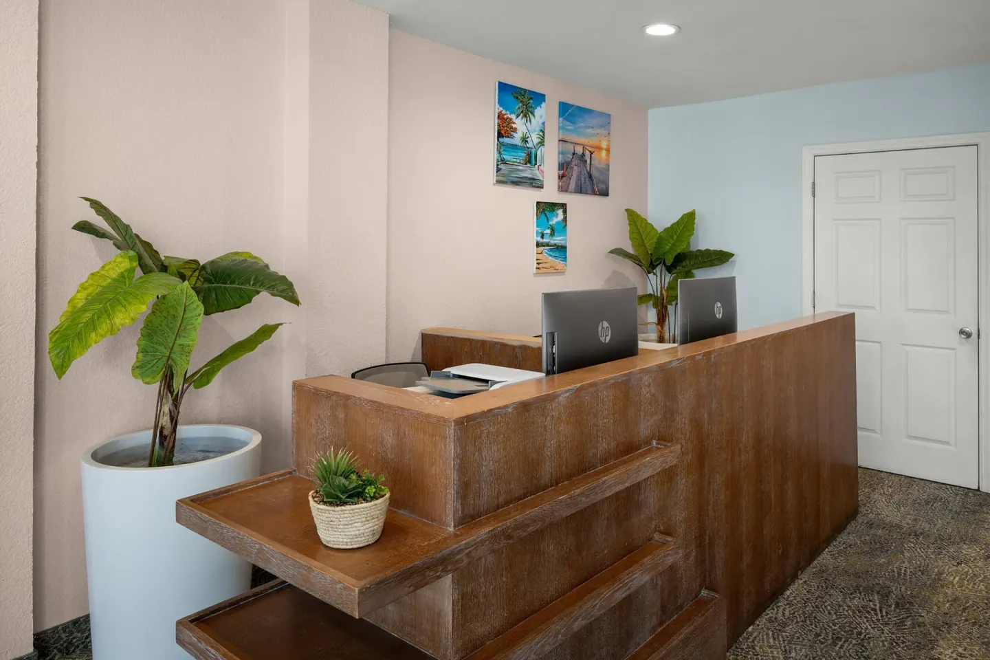 Wood reception desk with computers and plants at Courtyard Nassau Downtown/Junkanoo Beach.
