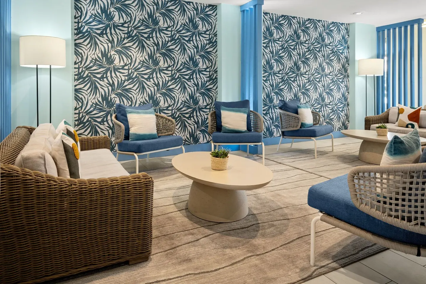 Seating lounge at Courtyard Nassau Downtown/Junkanoo Beach with wicker chairs and tropical wall pattern.