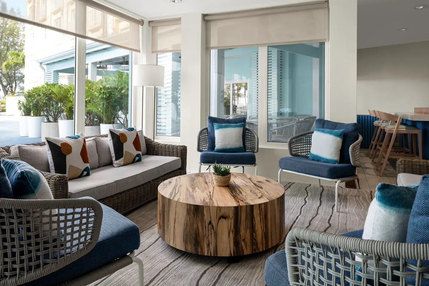 Windowed lounge at Courtyard Nassau Downtown/Junkanoo Beach with wicker seating and a round wood table.